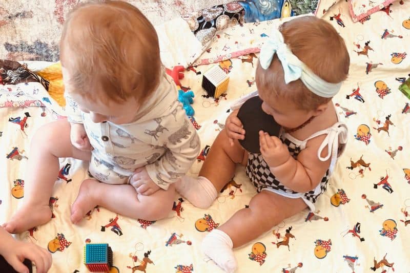 Adorable children engaging in a playful moment on a colorful blanket, highlighting the importance of supportive birth communities.