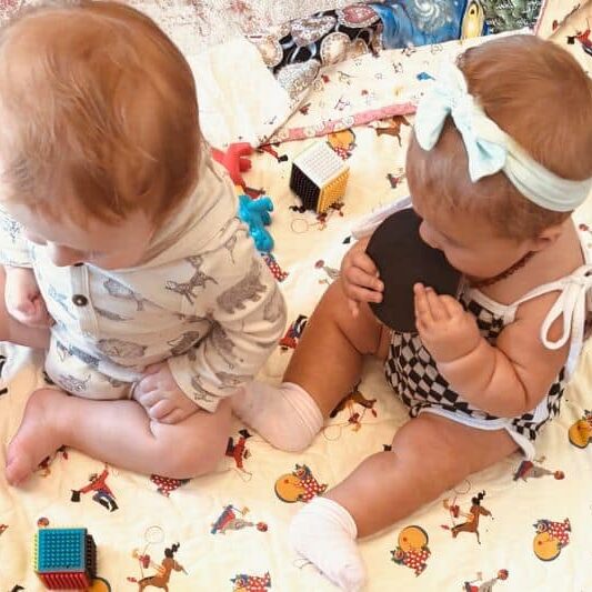 Adorable children engaging in a playful moment on a colorful blanket, highlighting the importance of supportive birth communities.